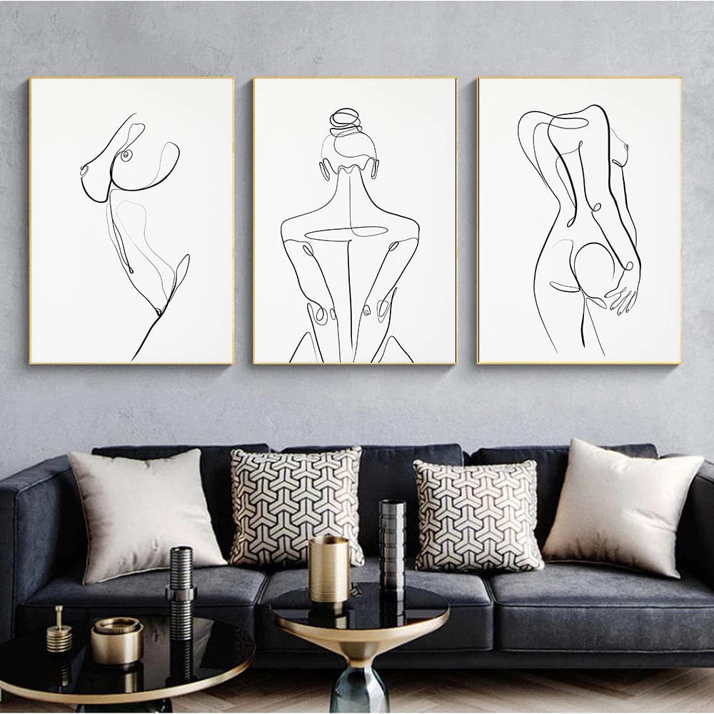Female body line drawing wall art, set of three black and white one line nude woman drawings in gold frames above a navy sofa