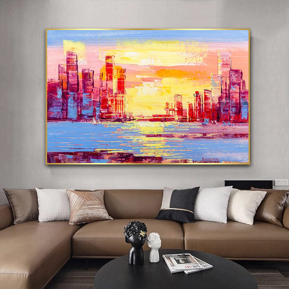 Abstract city landscape wall art, pink and yellow sunset over a skyline reflecting on blue water with a thin gold frame