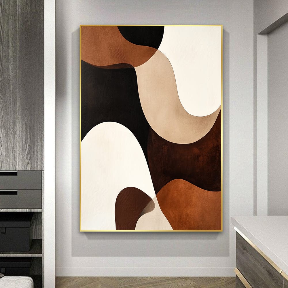 Abstract brown, beige and black fluid shapes wall art in a thin gold frame hanging on a gray wall