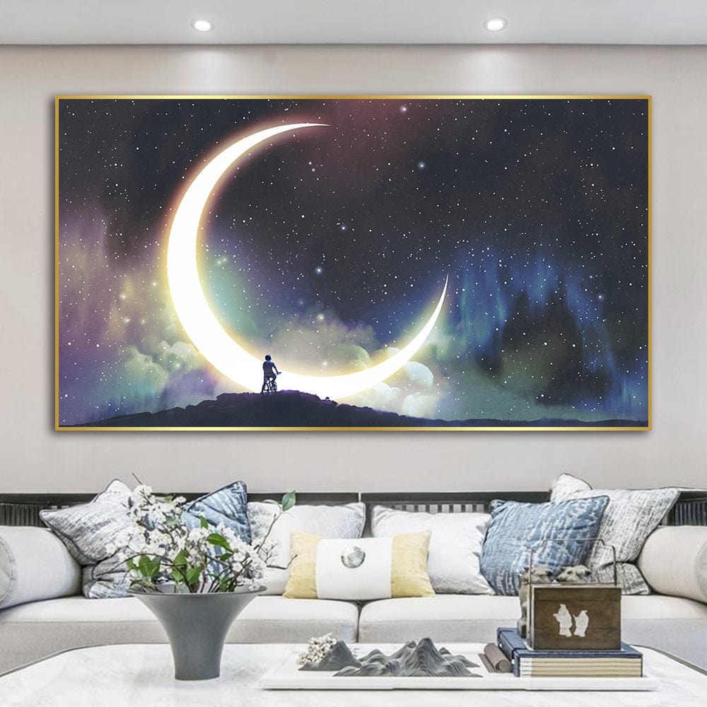 Cosmic moon landscape wall art, glowing crescent moon over a starry sky and a figure on a hill in a gold frame above a sofa
