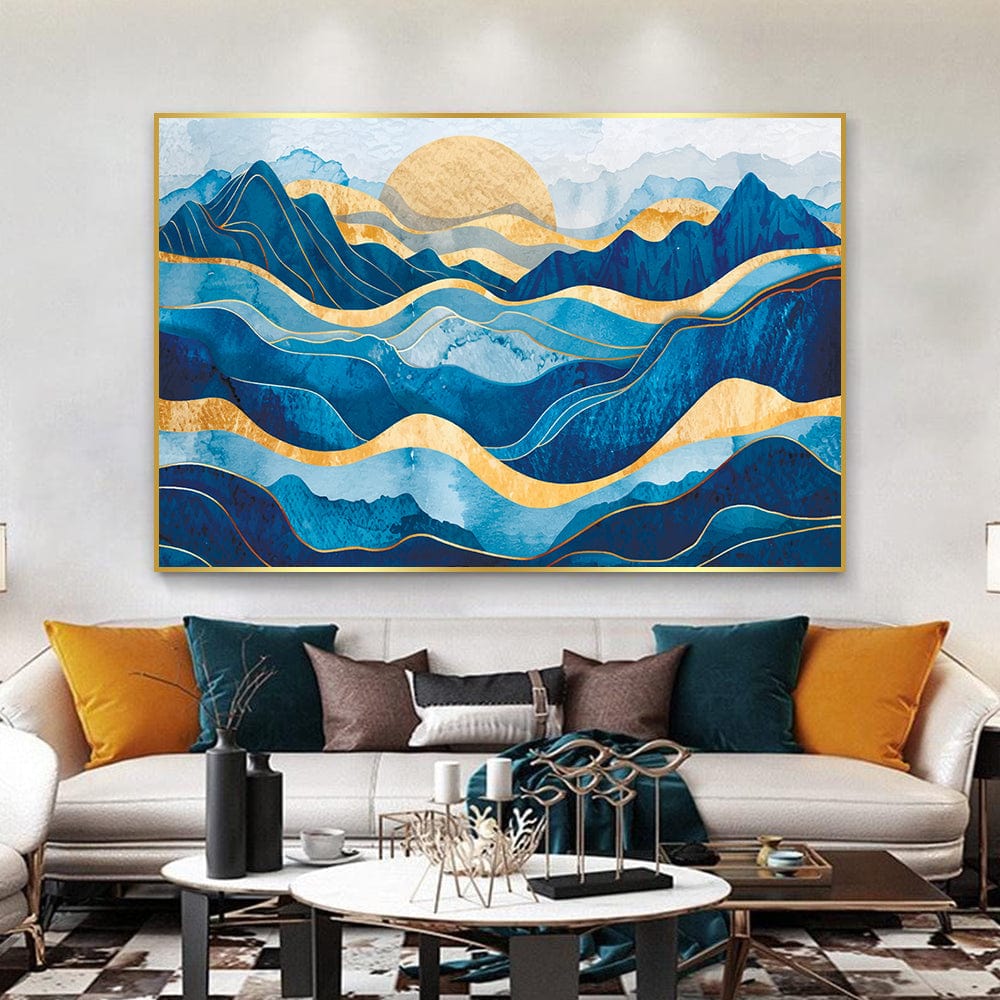 Abstract blue and gold mountain landscape wall art with sweeping waves and a golden sun above a sofa