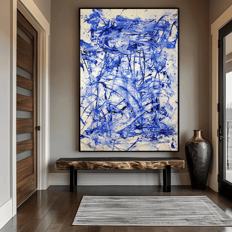 Blue abstract expressive marks wall art in a black frame hanging above a wooden bench in a hallway