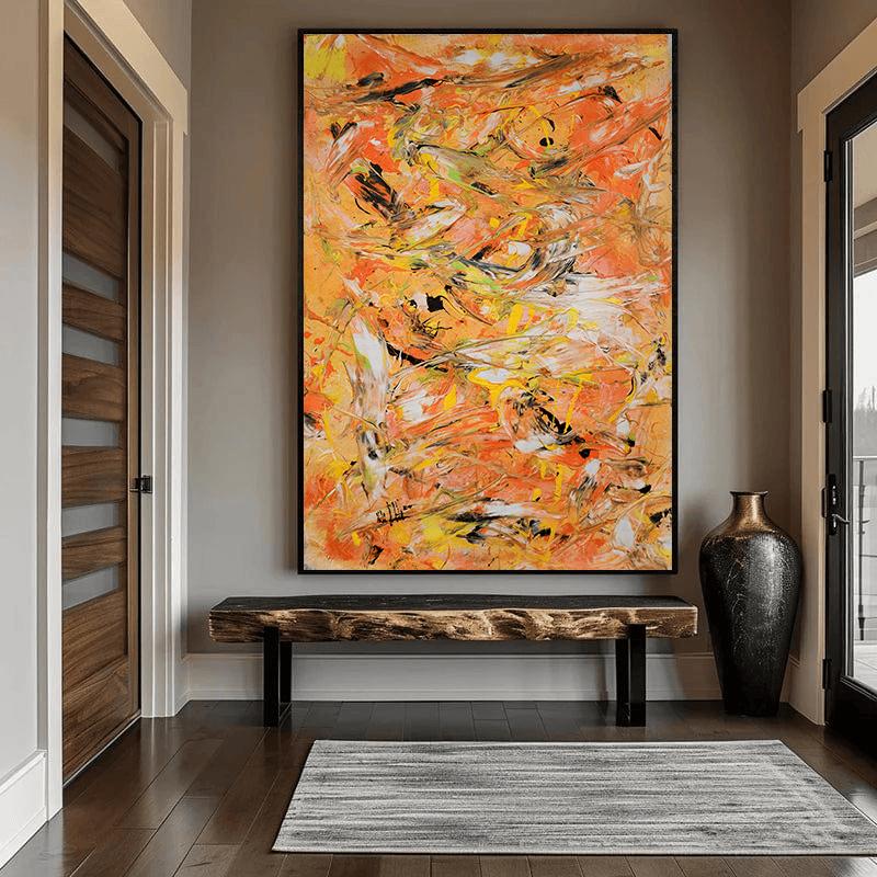 Vibrant orange abstract painting wall art in a black frame hanging in an entryway above a rustic wooden bench