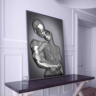 Decorative wall art of a silver abstract figure on a black frame in a room with white walls and a dark console table.