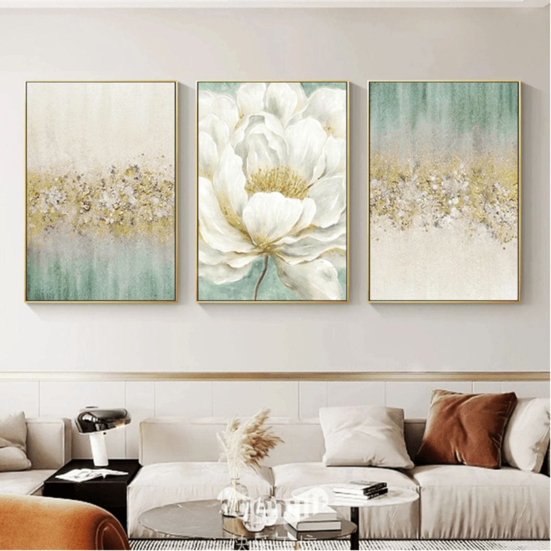 Verdant Gold wall art set, three framed abstract white flower paintings with gold leaf accents hanging above a sofa