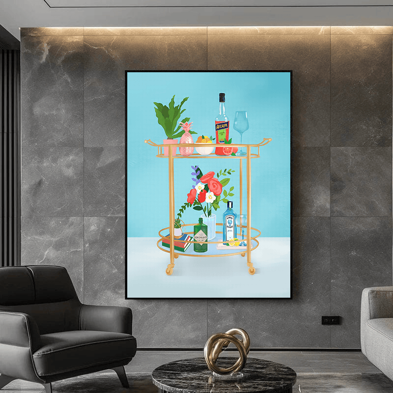 Bar cart wall art painting, golden cart with bottles and flowers on a blue background in a black frame on a marble wall