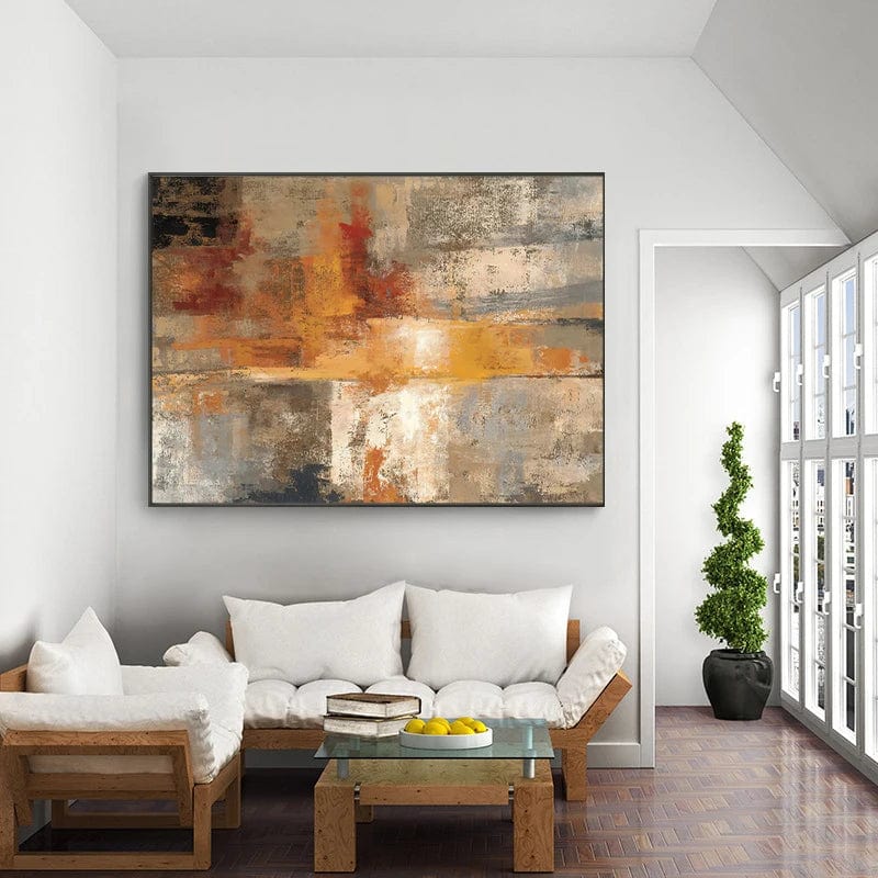 Abstract golden warmth sunset landscape wall art in a black frame above a white sofa in a bright living room