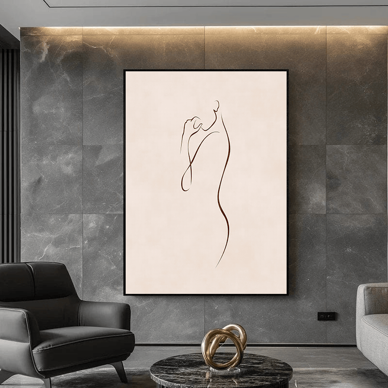 Black and white abstract female form wall art in a black frame hanging on a dark grey marble wall above a modern armchair