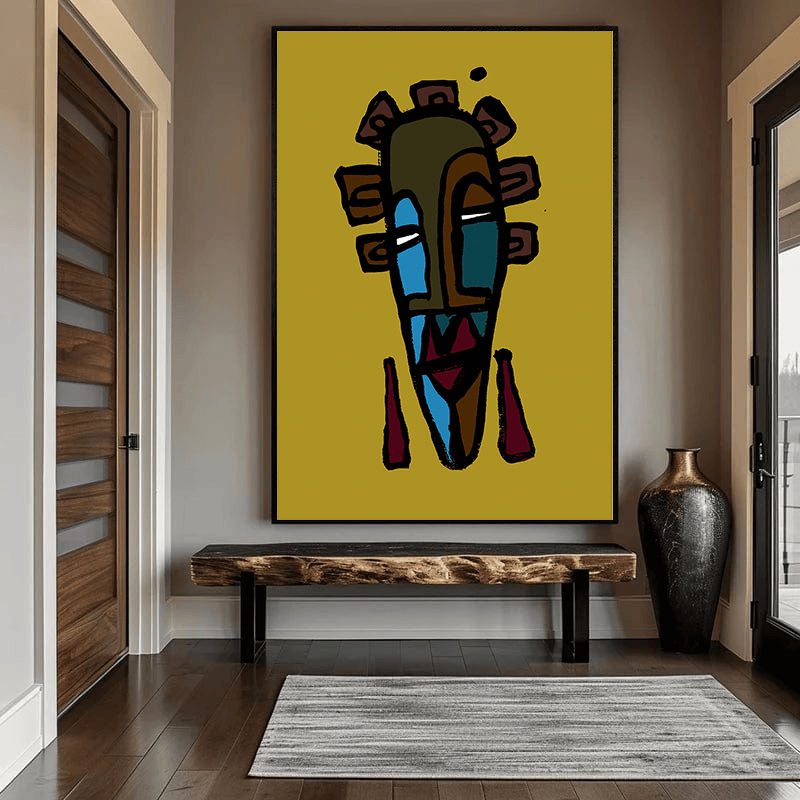 Abstract tribal mask wall art, stylized figure in mustard yellow and blue on a black frame above a wooden bench