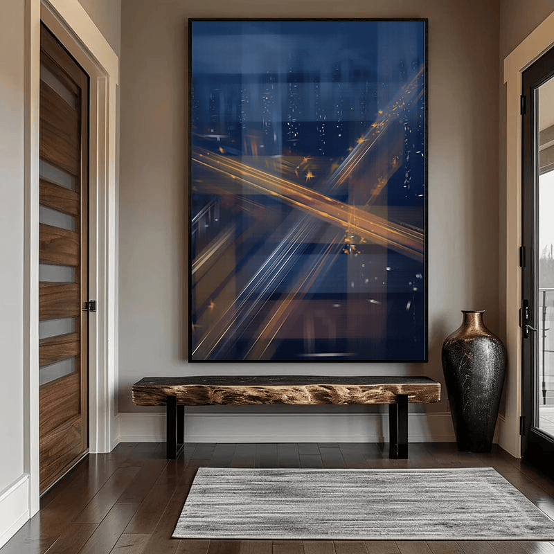 Abstract city light trails wall art, golden streaks across a dark navy night sky above a wooden bench in an entryway