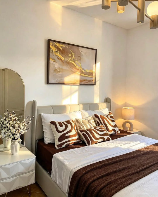 Rosegold Marble, gold leaf on taupe and cream, framed above a bed with brown and cream cushions
