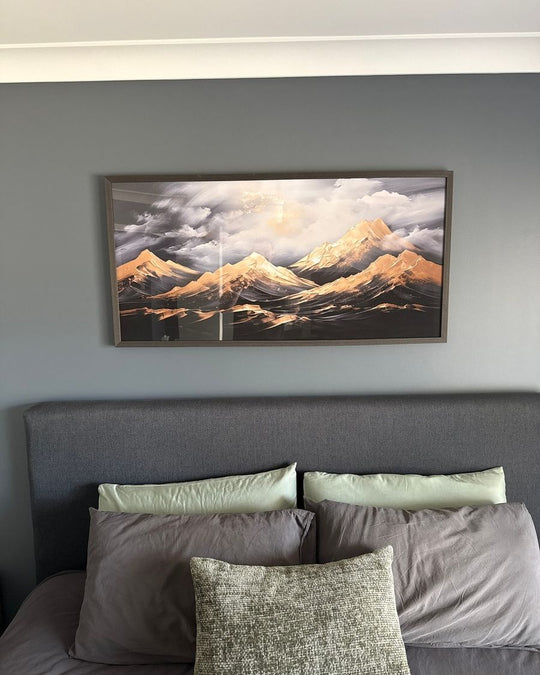Framed Golden Heights mountain print above a grey upholstered bed