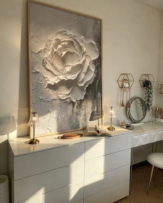 Large framed Rose Onyx painting, a textured white flower on grey, leaning above a white chest of drawers lit by low sun